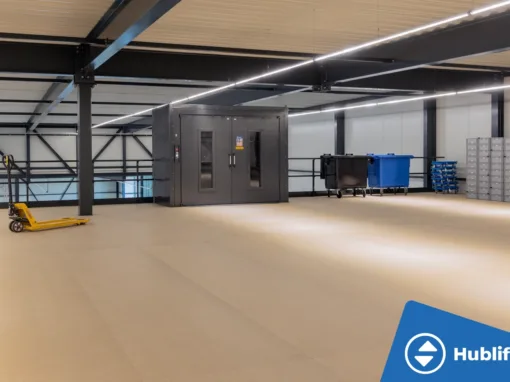 Industriële goederenlift met zelfdragende schacht en rood platform, deuren open