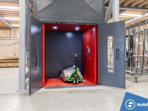 Industriële goederenlift met zelfdragende schacht en rood platform, deuren open