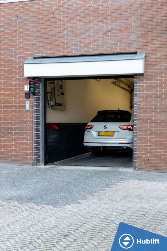 Witte auto in een autolift achter een geopende garagedeur