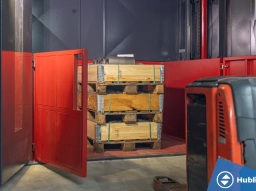 Industriële goederenlift met zelfdragende schacht en rood platform, deuren open