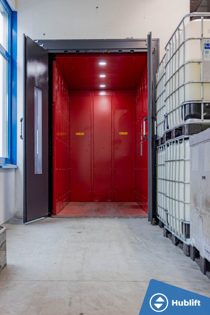 Goederenlift 5000 kg met rode cabine en openslaande deuren in een cosmeticabedrijf in Duitsland