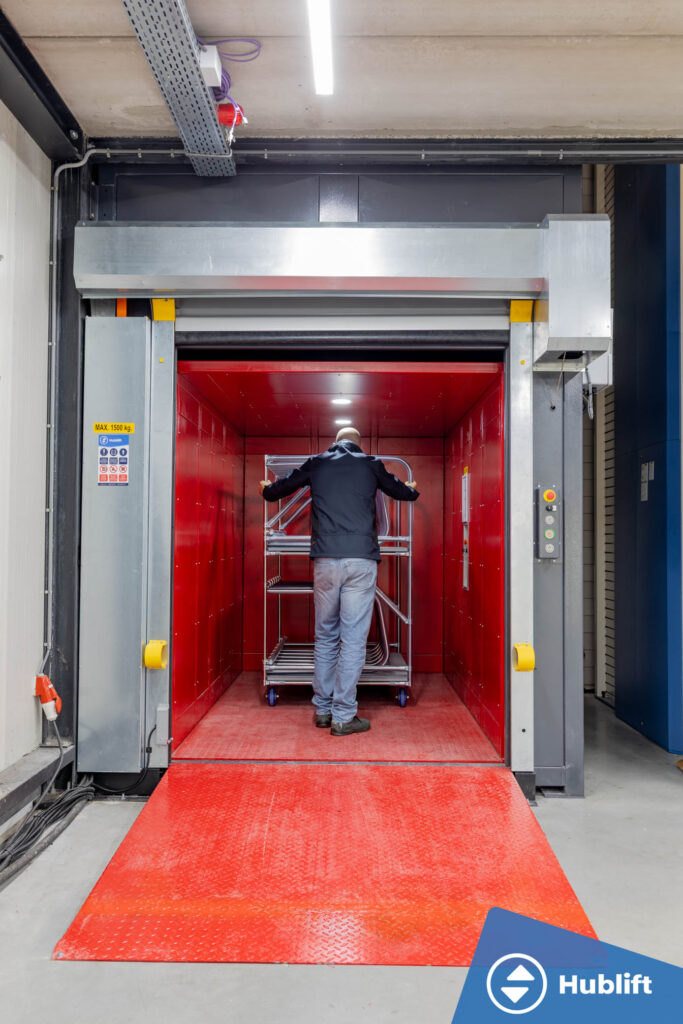 Employee loading the red car of the goods lift with attendant