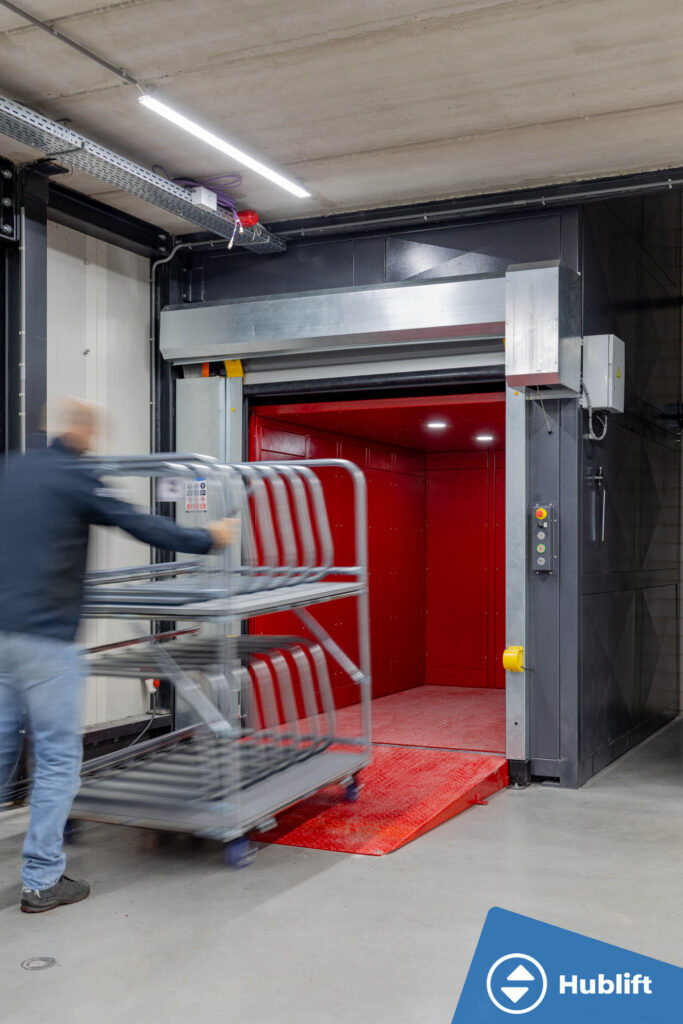 Employee wheeling a roll container into the goods lift via the loading ramp