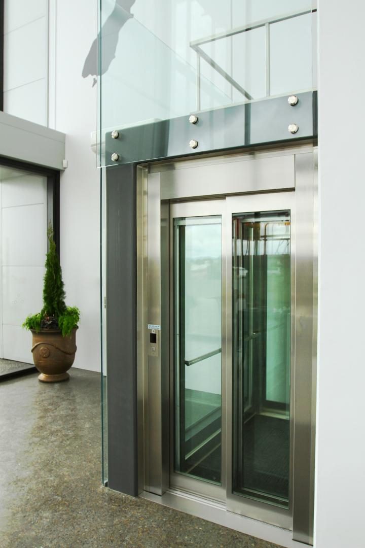 Personenlift met glazen deuren en RVS portaal