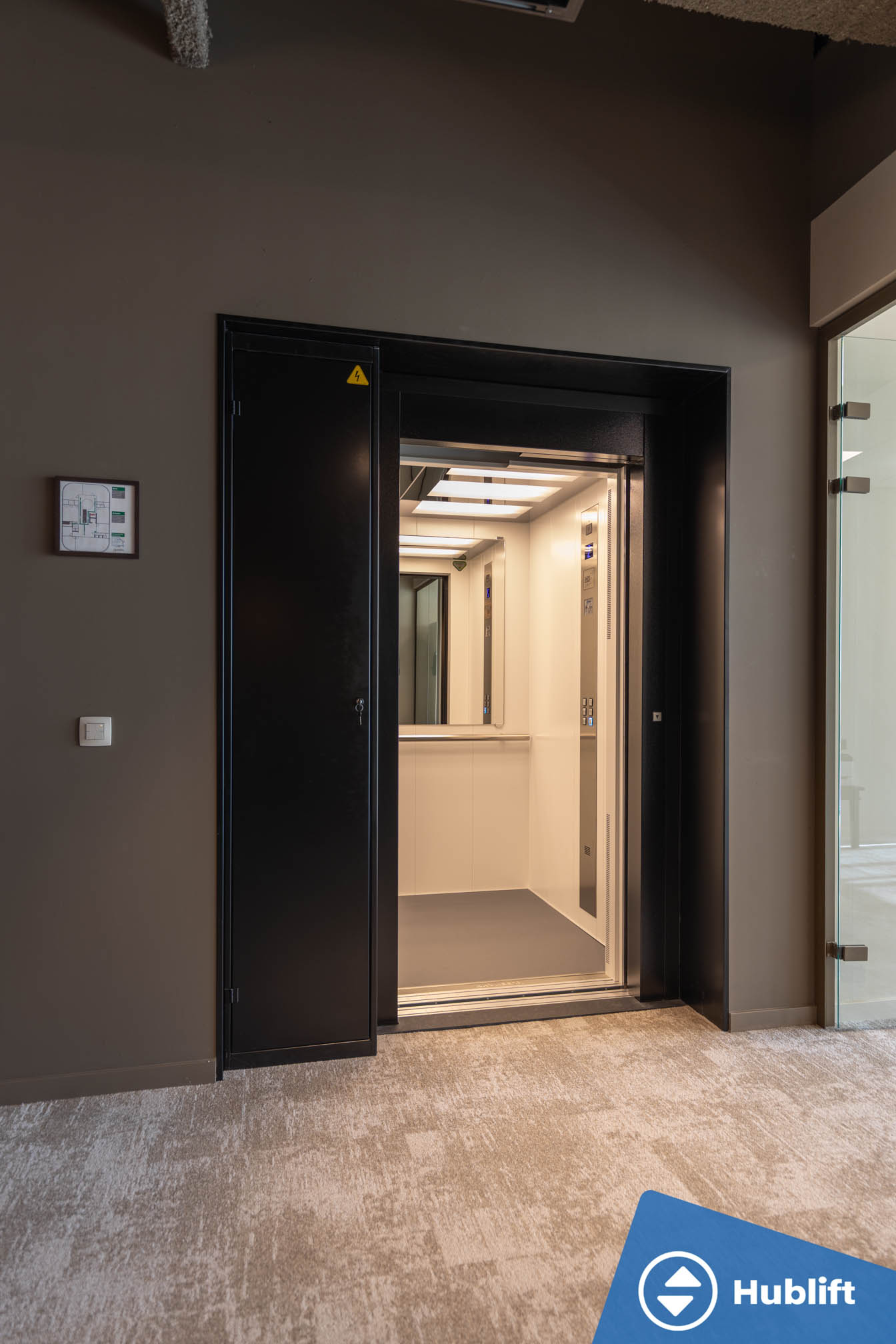 Open personenlift met lichte cabine en spiegel in kantoorgebouw